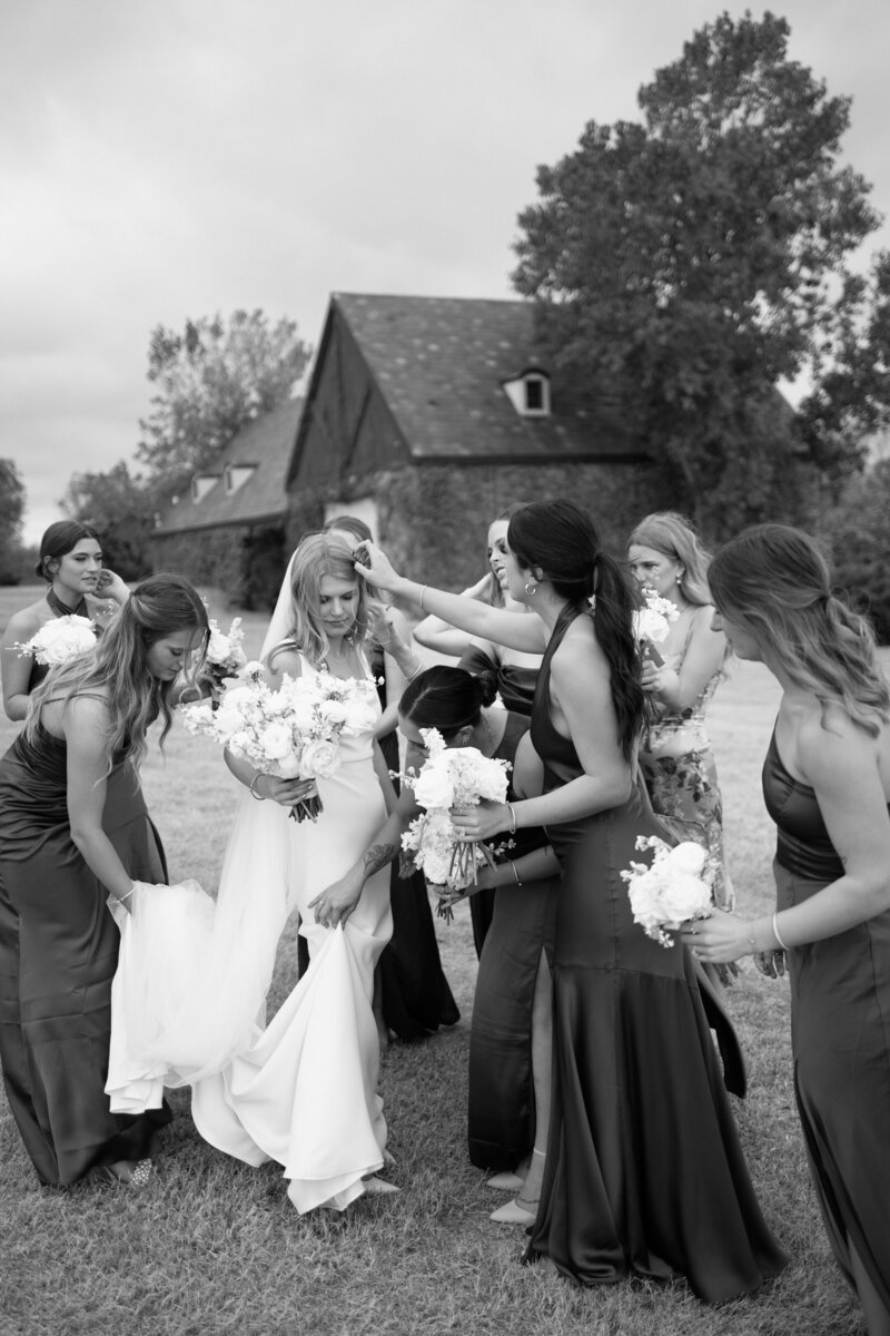 Bridesmaids adjusting bride’s dress and veil before ceremony – candid black and white wedding moment captured by Madison Dodd Photo