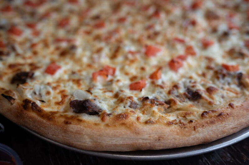 Close-up of Redo’s donair pizza with golden crust and diced tomatoes—handmade comfort food in Yarmouth