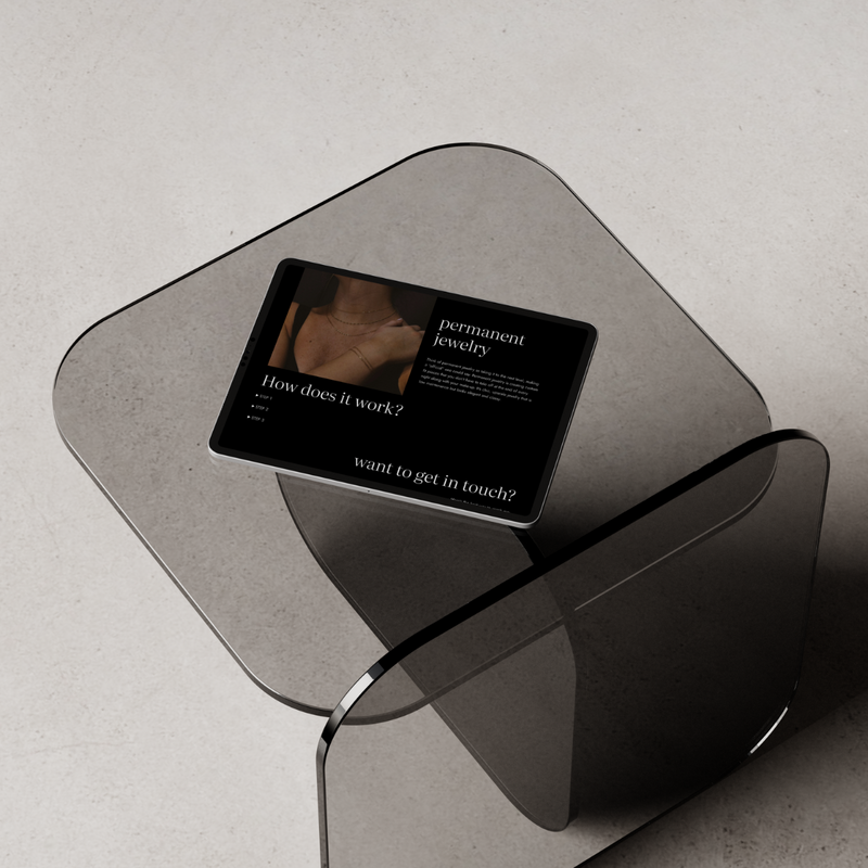 Stylized tablet mockup featuring a permanent jewelry website design by Allie Clark Designs, resting on an abstract modern chair.