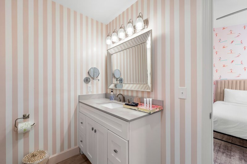 Coastal-inspired bathroom with wide vanity, large framed mirror, and stylish lighting, connecting to the primary bedroom.