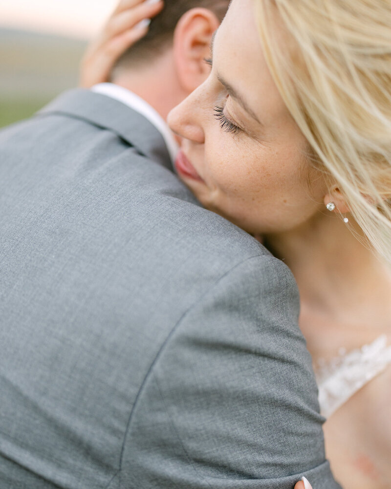 This romantic evening portrait captures the bride holding her groom at Saskatoon Farm, creating a heartfelt and intimate moment against the farm’s serene backdrop.
