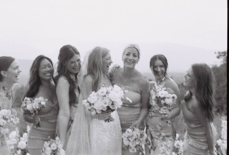 A bride poses with her bridesmaids, all smiling