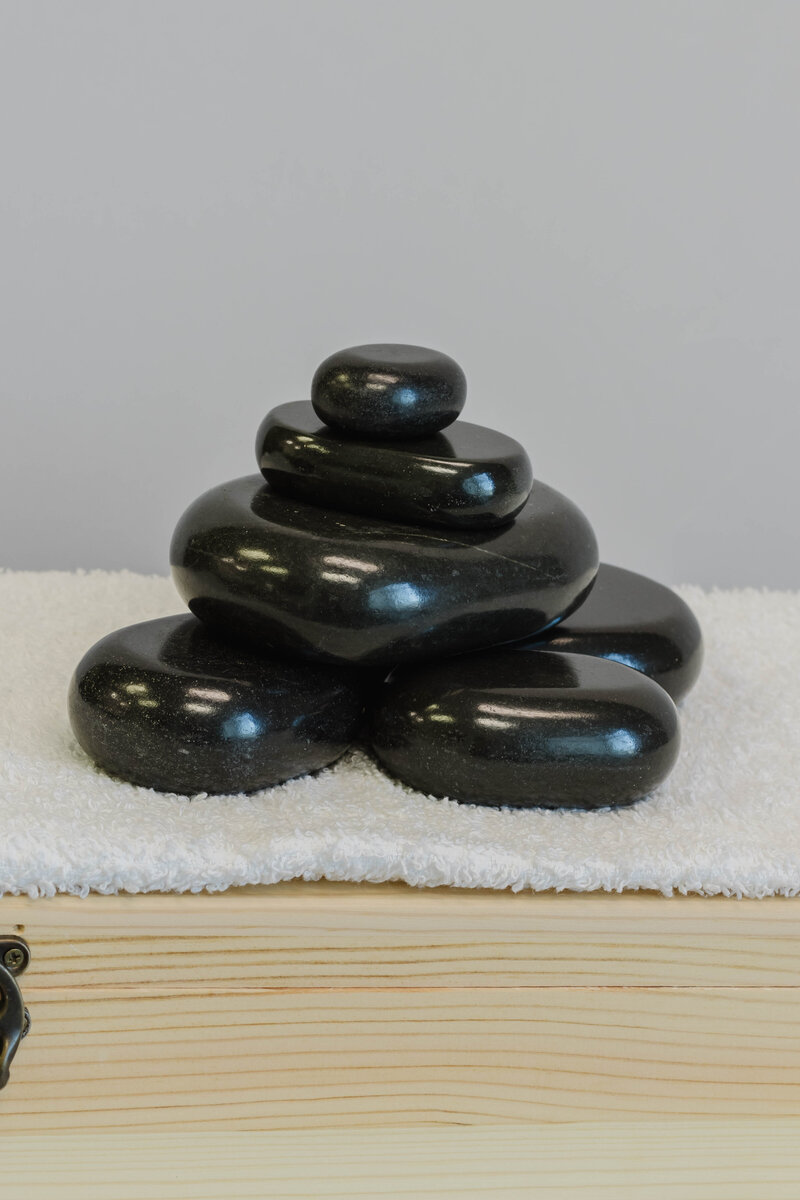Stack of black hot stones on a white towel — professional massage therapy tools