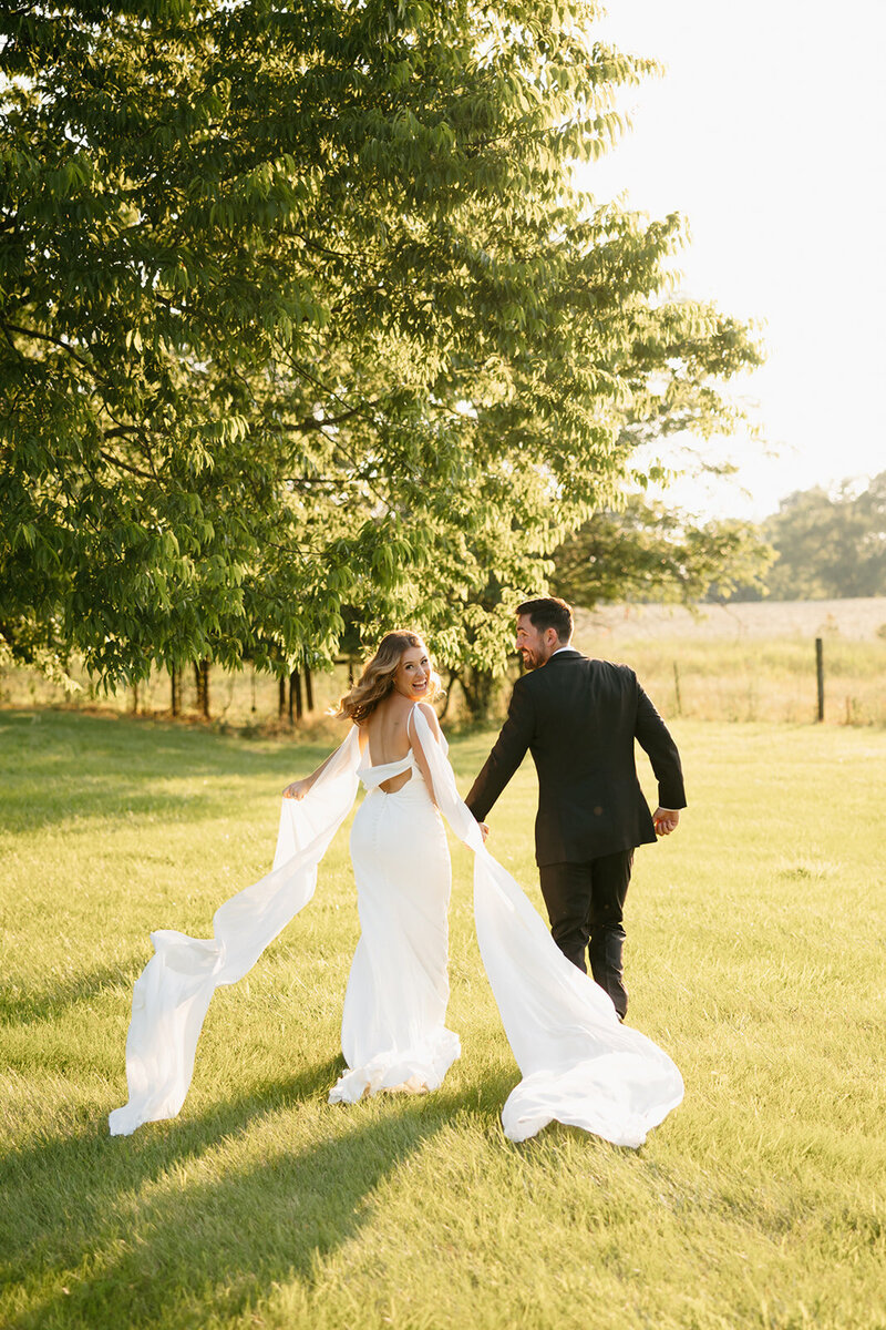 Bride and groom running through grass at Nashville wedding