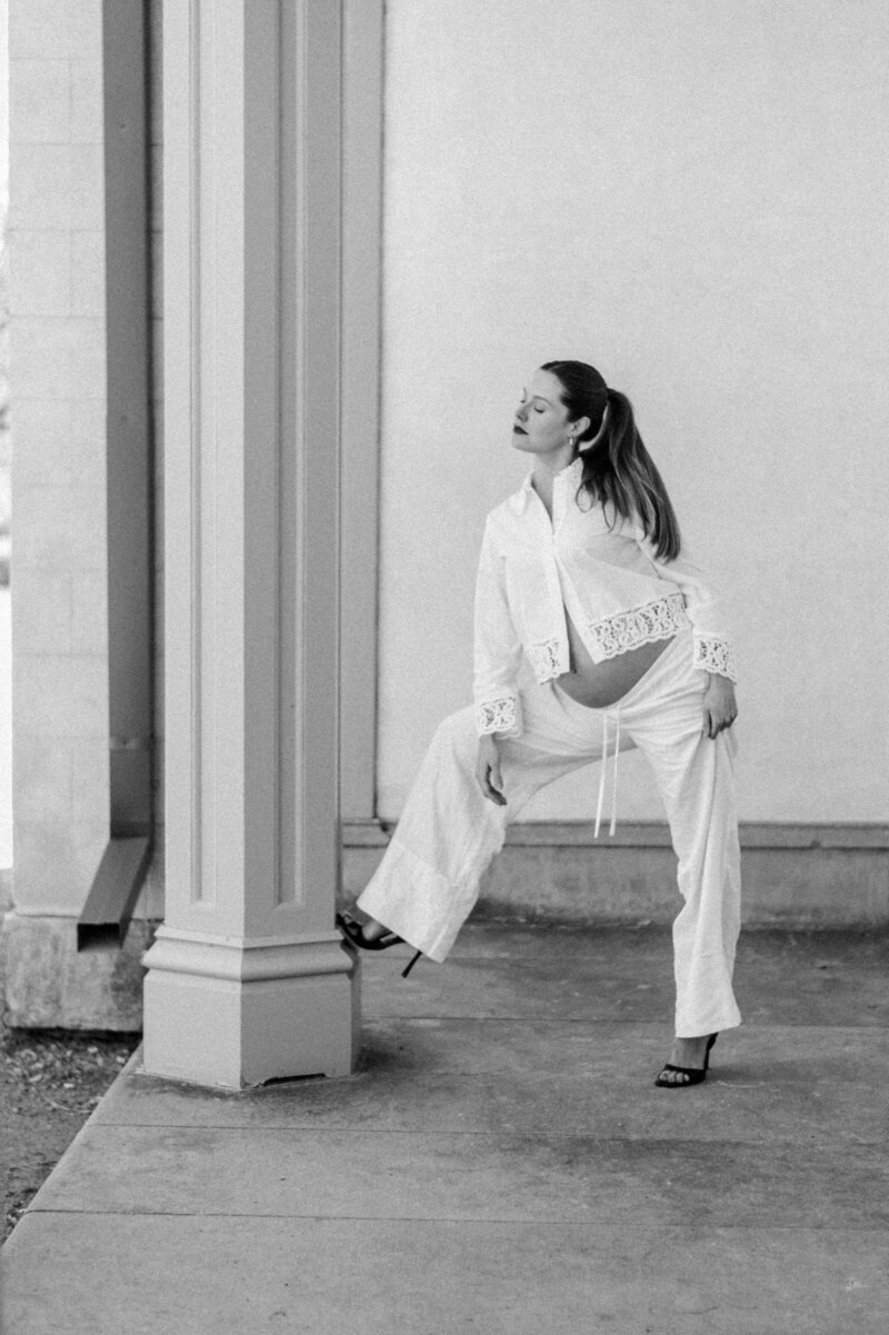 a woma is standing with her foot up on the pillar of an old chaming castle looking posh and stunning