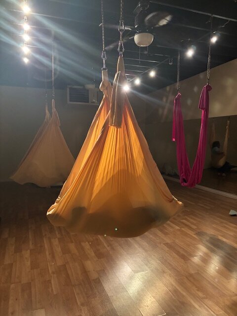 keri nola with hands on a client's back in a gold colored somatic swing