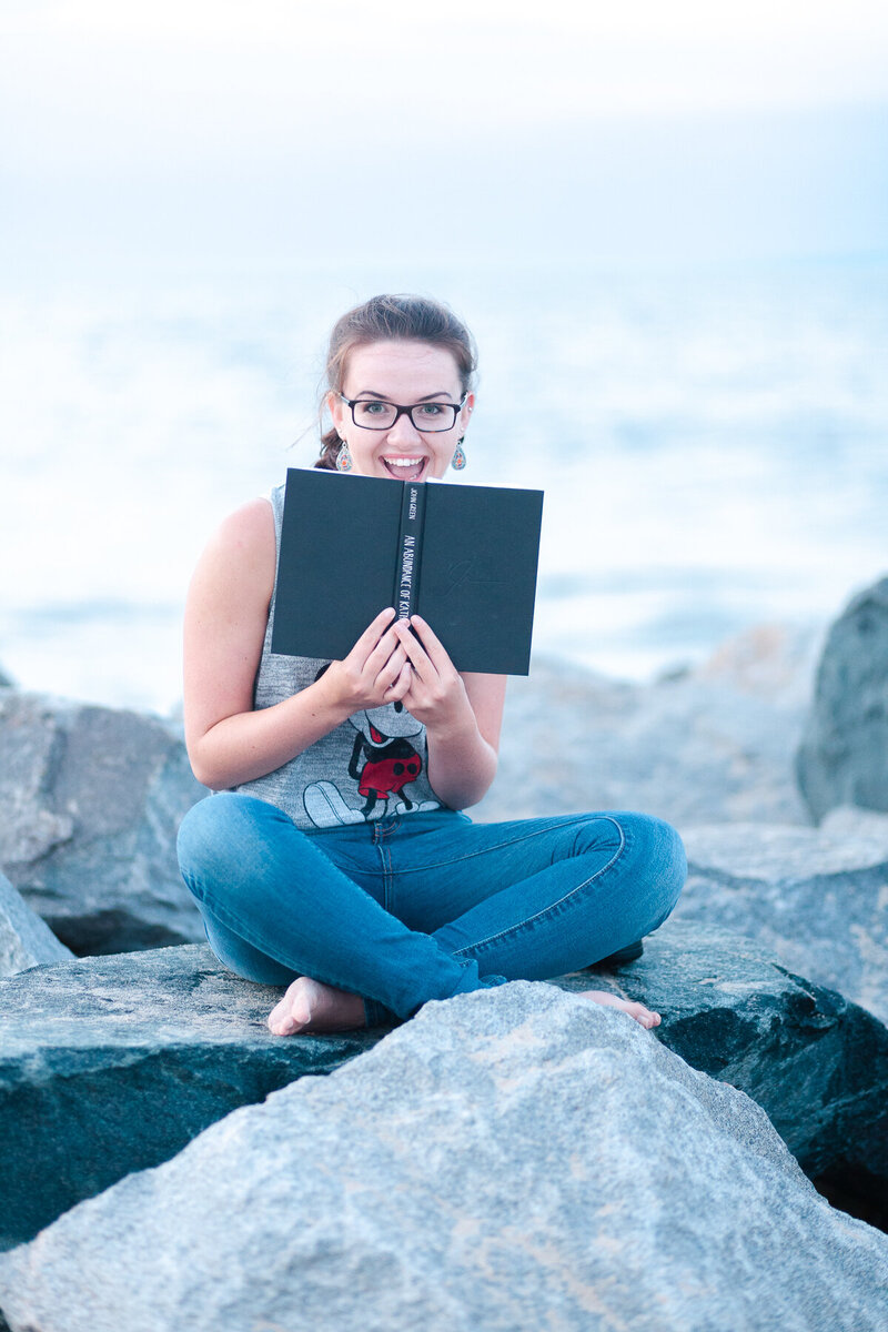Girl at the beach on rocks reading
