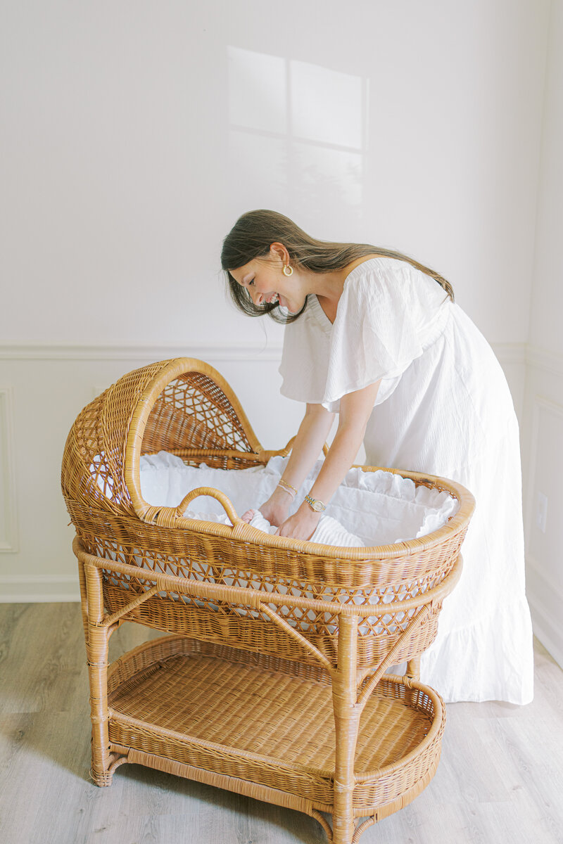 mom reaching into bassinet for baby