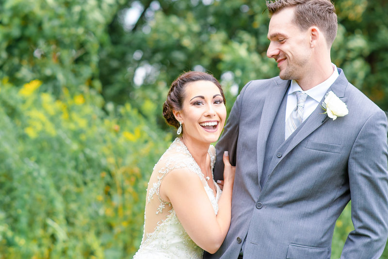A bride and groom laugh together during their portraits