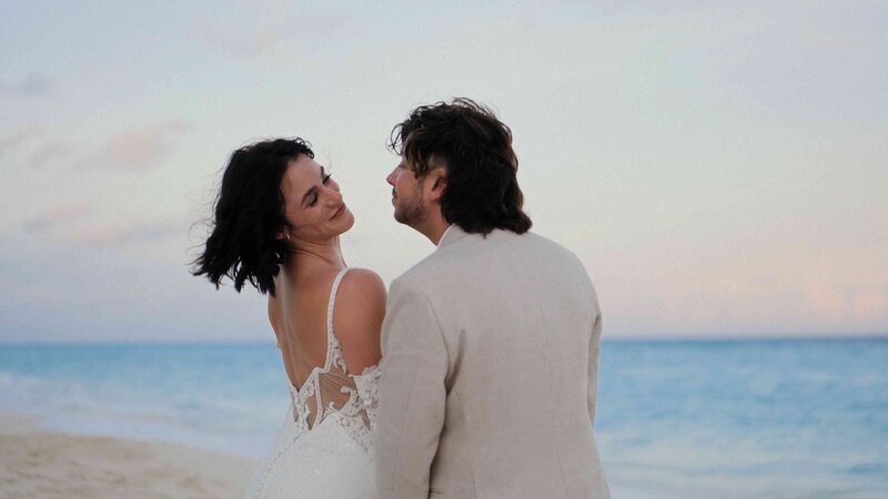 Couple holding hands and smiling on a sunny Cancun beach.