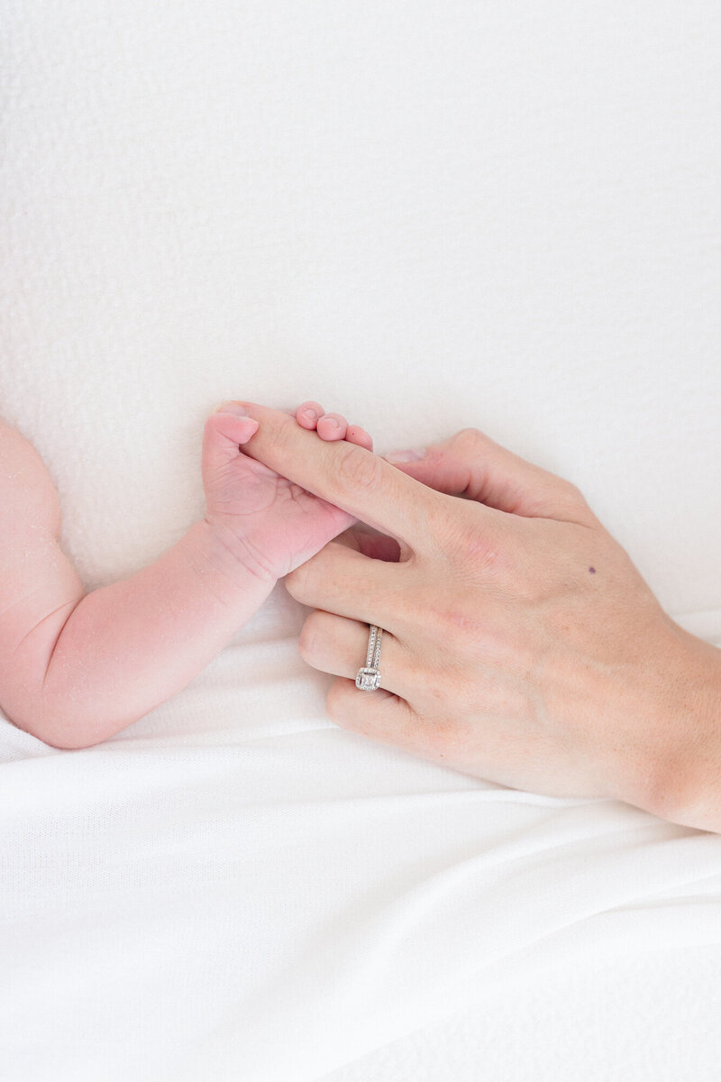 Portrait of a newborn baby hand holding on to mom's finger in a bright northern kentucky photography studio