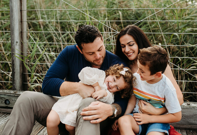 Family with daughter and son  hugging on pier near tall grass in Washington DC