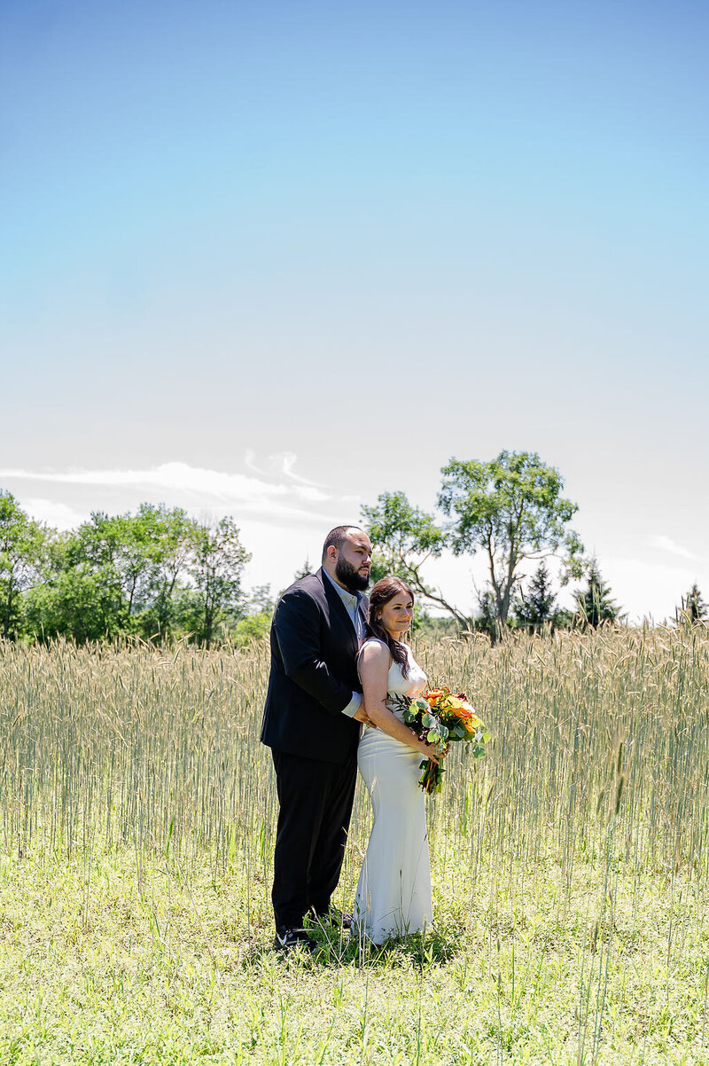 Bride and groom standing in a field of tall grass