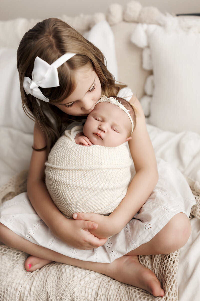 Beautiful image of baby girl in big sister's arms