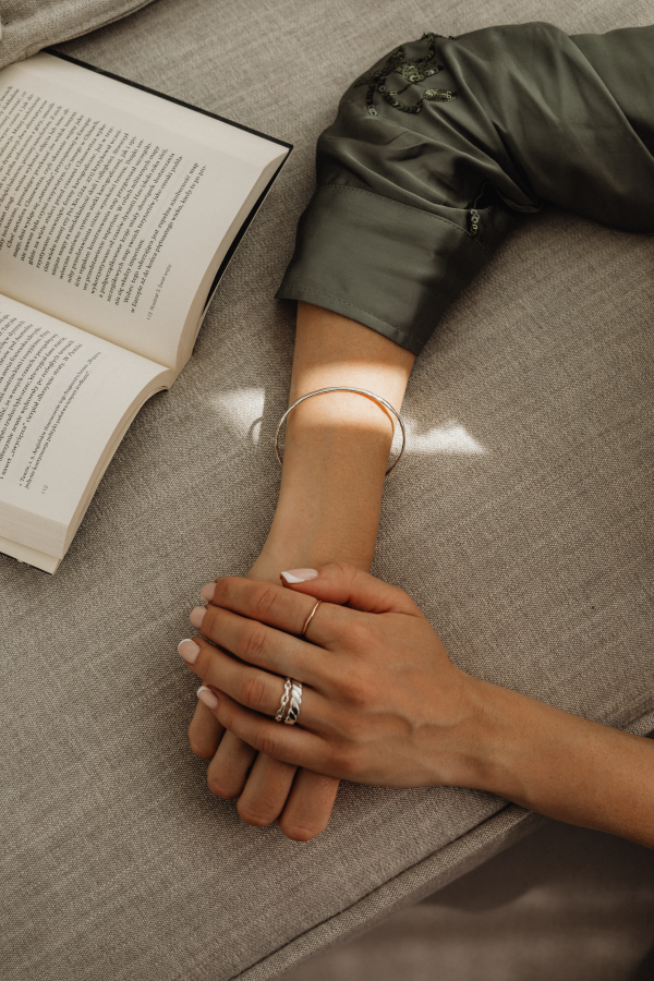 Arms of a woman laying on a couch with a book open ready to read | Brand By Design