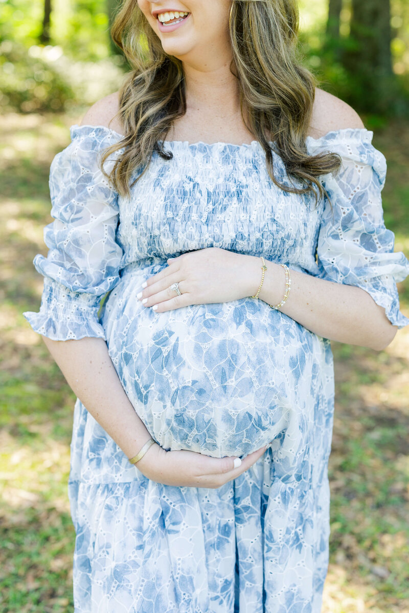 Woman smiling holding pregnant belly during maternity photography session