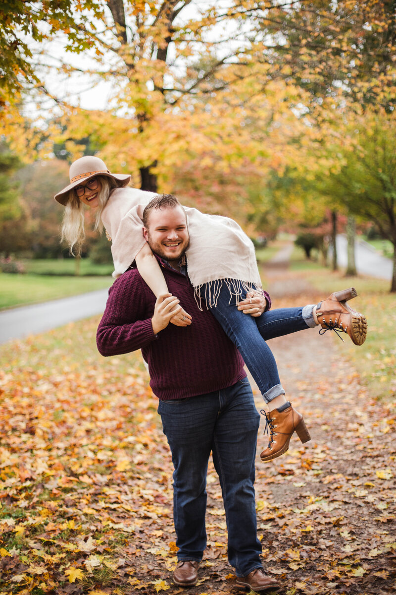 man lifting woman during fall outdoor engagement session