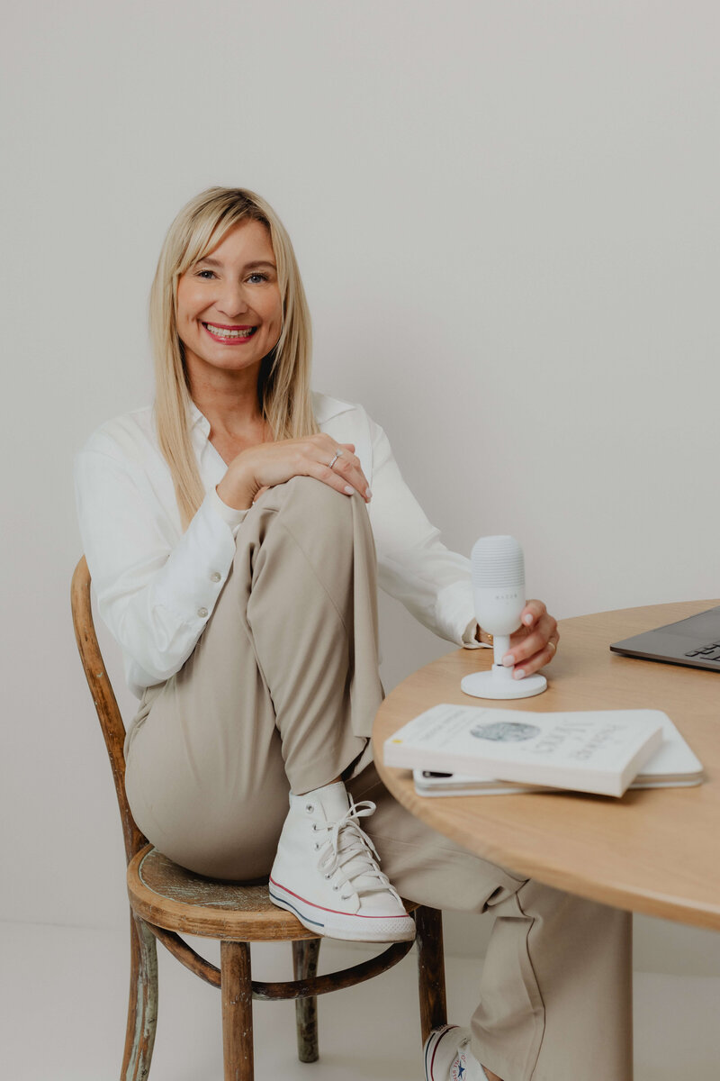 A women sitting at aa table holding onto a microphone. 