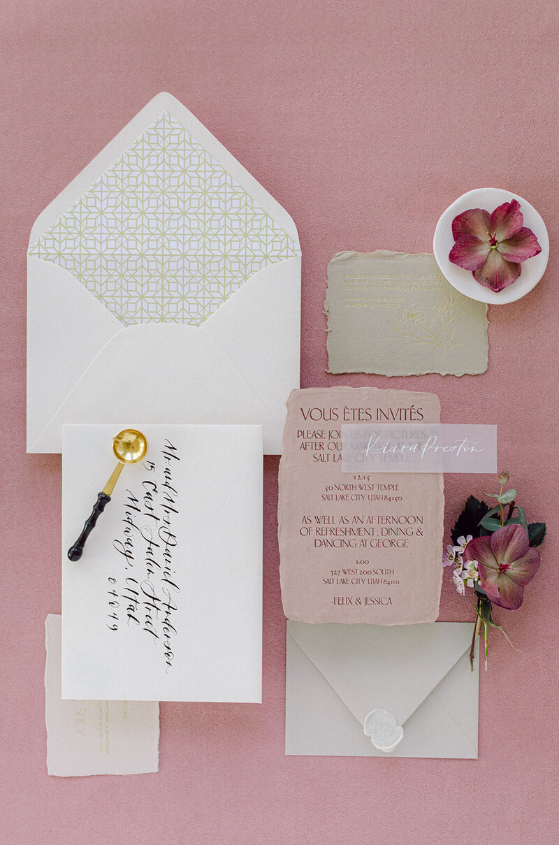 Light pink suede mat with blush-toned invitations and florals