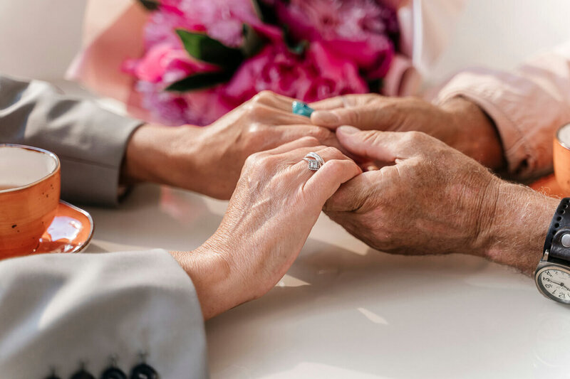 Close-up of two women holding hands in prayer, with pink roses in the background. Represents encouragement, support, and the personal, faith-centered approach of Nita Tin’s coaching.