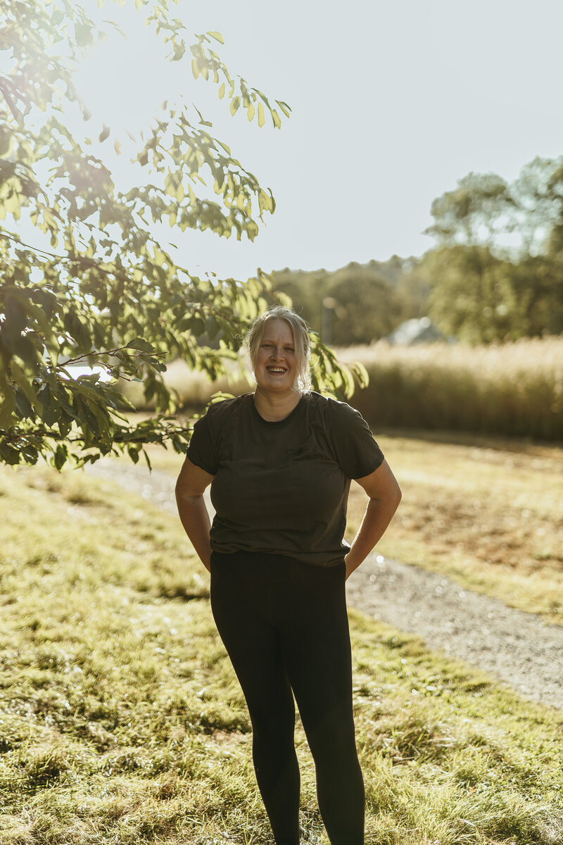Porträtt på fotografen Fia Wolle med ett gräsfält och vatten som bakgrund i Stockholm