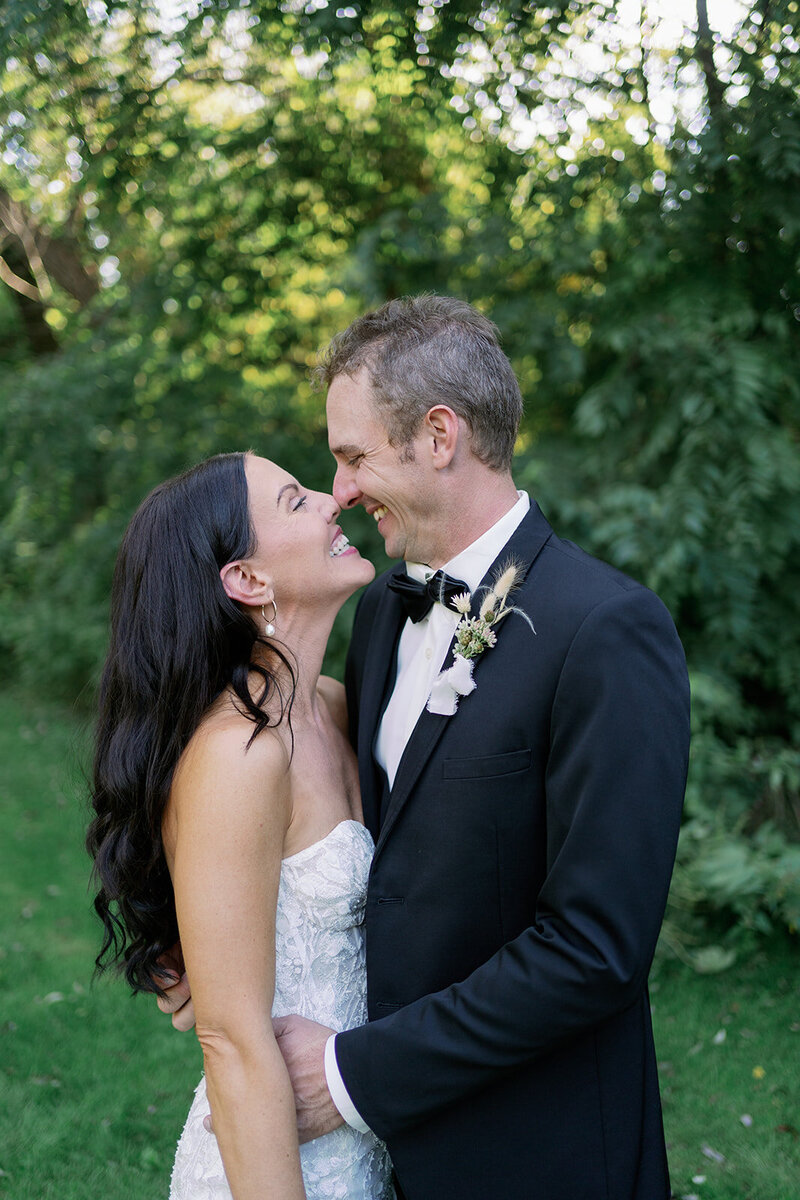 Bride and groom laughing with their noses pressed together during candid bridal portraits at the Glasshouse Community venue.