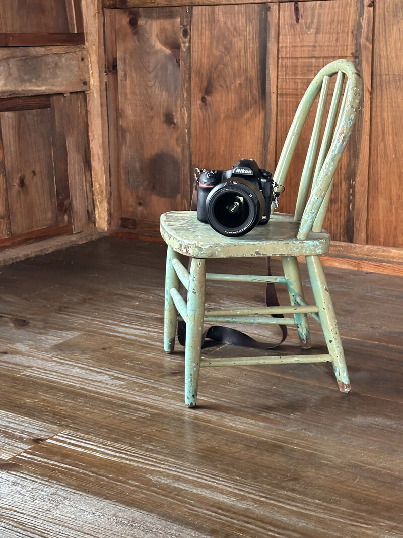Canon camera sitting on wooden chair in a studio