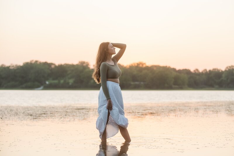 a girl posing while standing in water at sunset