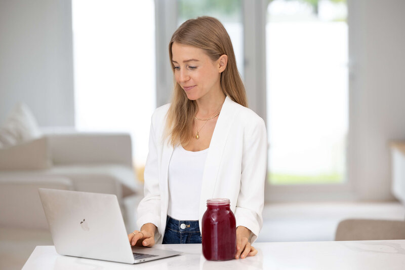 Olivia Budgen working on a laptop, promoting the Institute for Integrative Nutrition and online health coaching opportunities