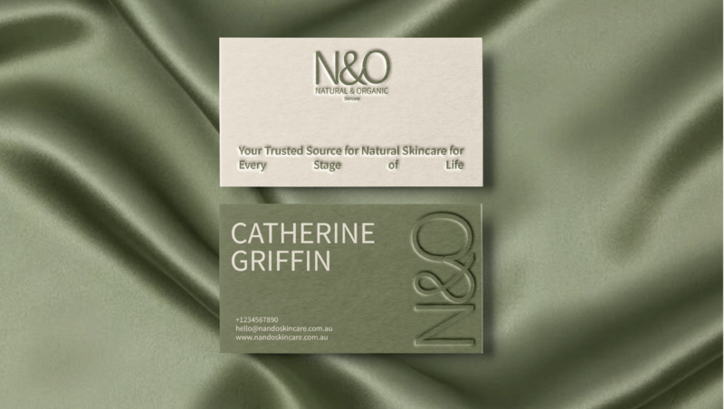 White clothing tag with "No Filtr" in light script, attached by black ribbon on soft gray fabric with subtle folds.