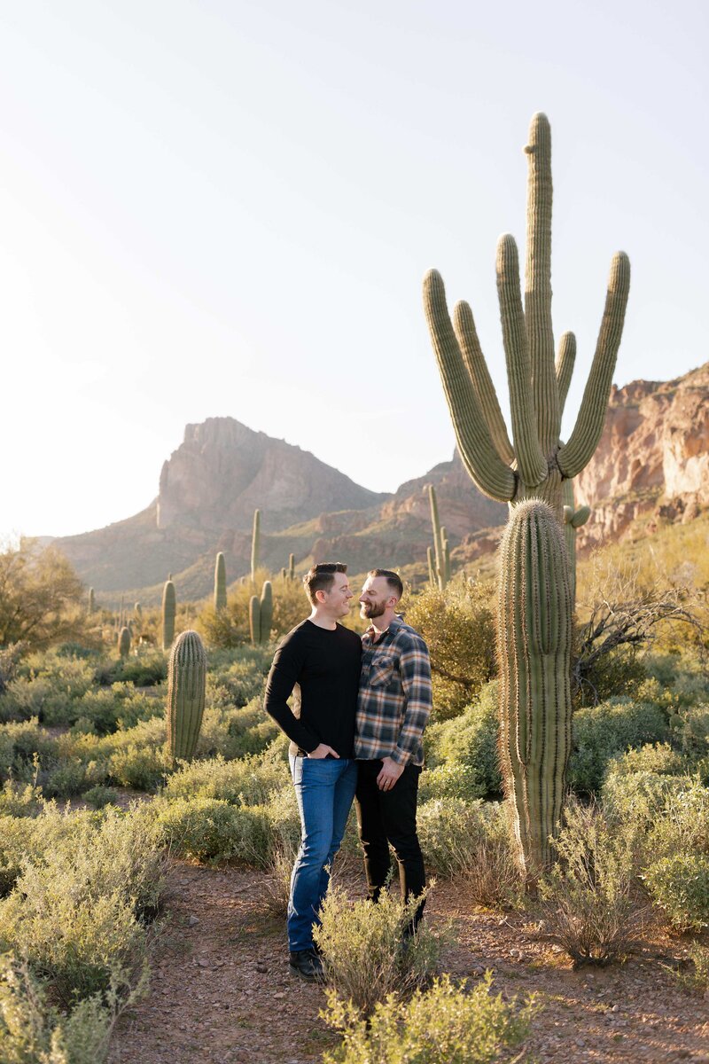 Couple side hug and cuddle in the desert for engagement photos.