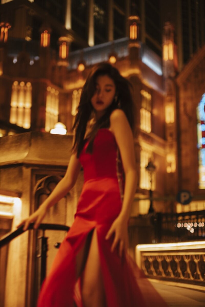 Destination couture photoshoot with a woman in. a red gown at night in the city.