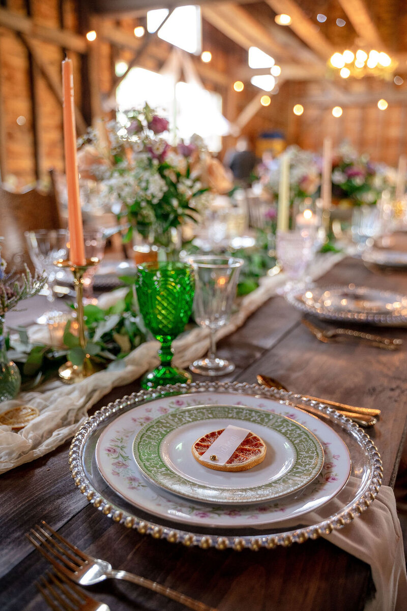 Close-up of wedding table decor with flowers, candles, and glassware.