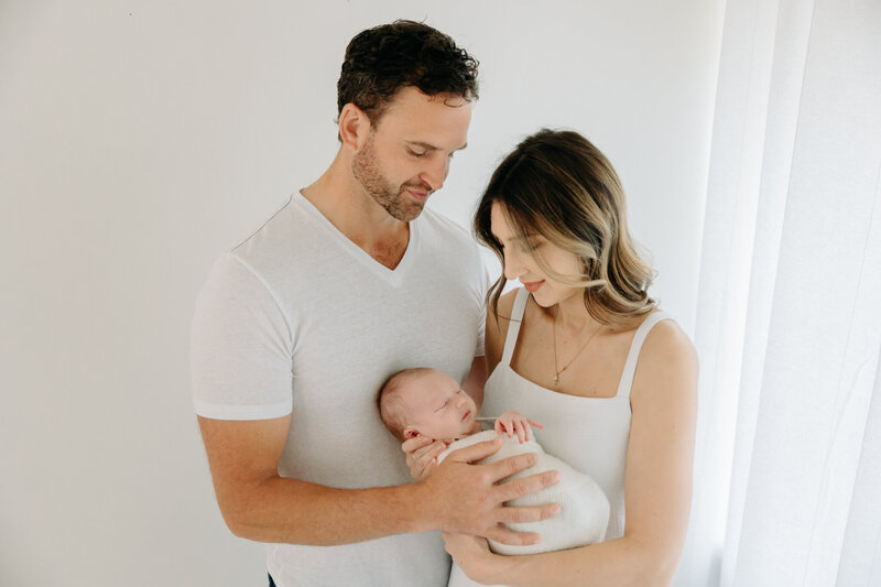 newborn photos on white wall with mom and dad