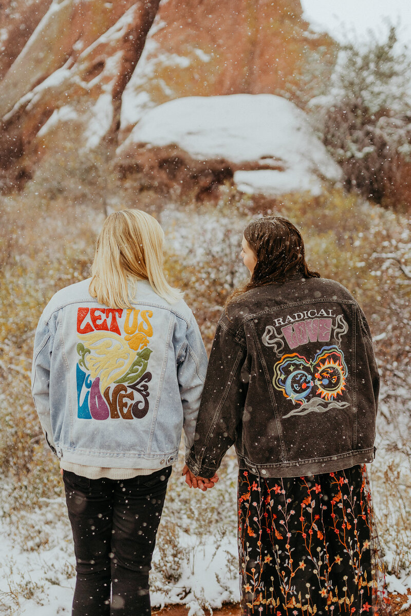 couple with colorful denim jackets hold hands