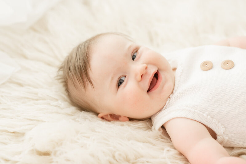 Little girl in pink smiling at camera with cake for first birthday photo session