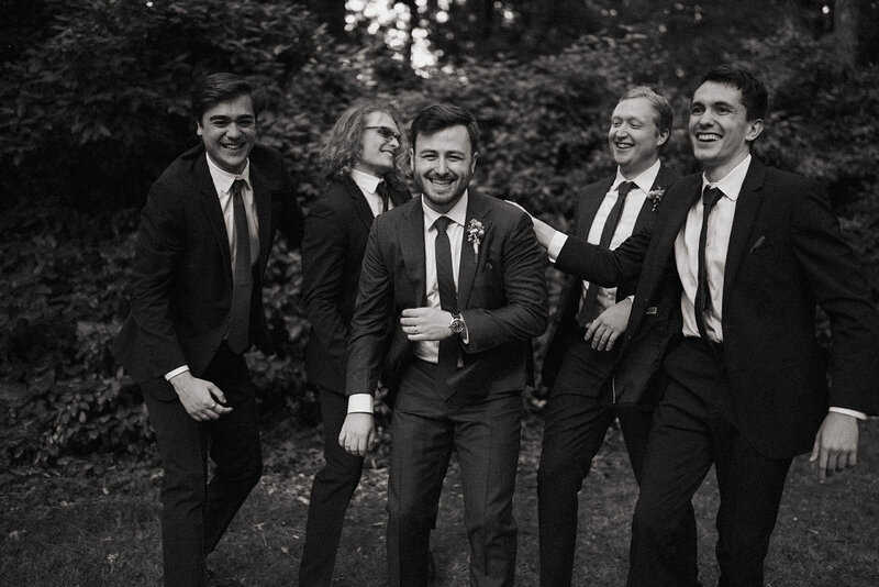 Groom laughing with his groomsmen in a candid moment outdoors, captured by a Spokane wedding photographer.
