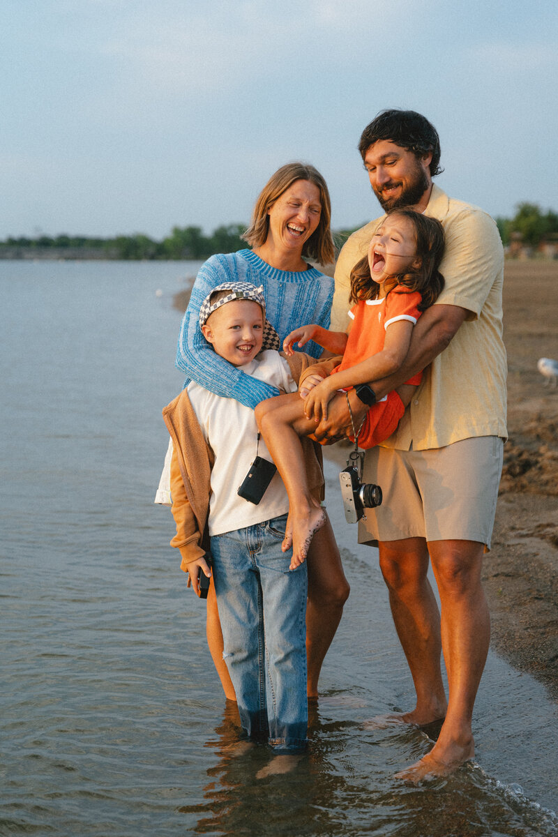 Beautiful family smiling and laughing at the beach on an overcast day