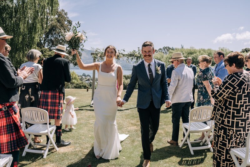 a bride and groom exit wedding ceremony smiling down the aisle at mt vernon in akaroa
