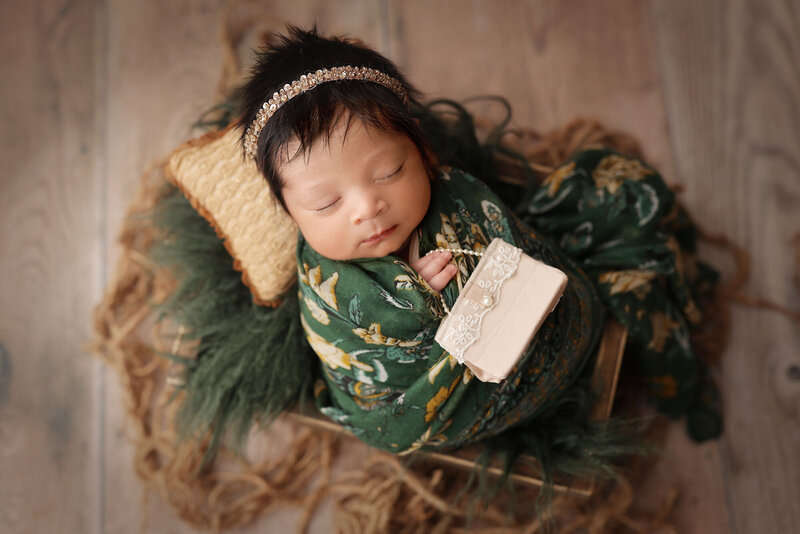 portrait of a sleeping baby girl on a green fur with a golden purse