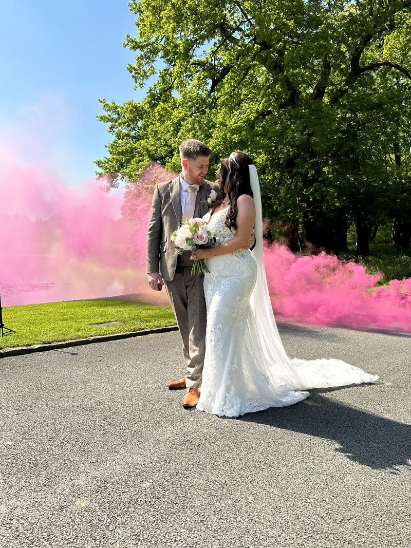 Pink smoke bomb behind the bride and groom