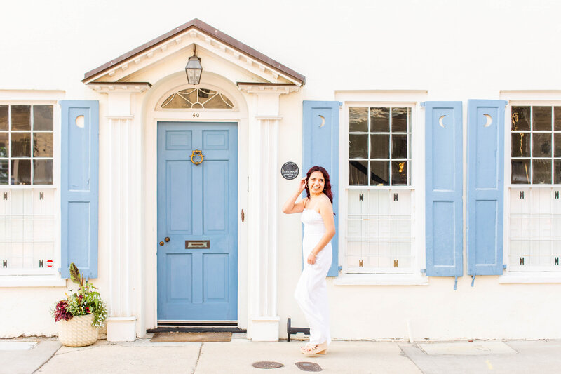 girl walking in front of historic blue white home with blue front door