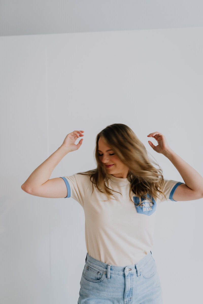 Megan Evans flipping her hair standing in front of a white wall