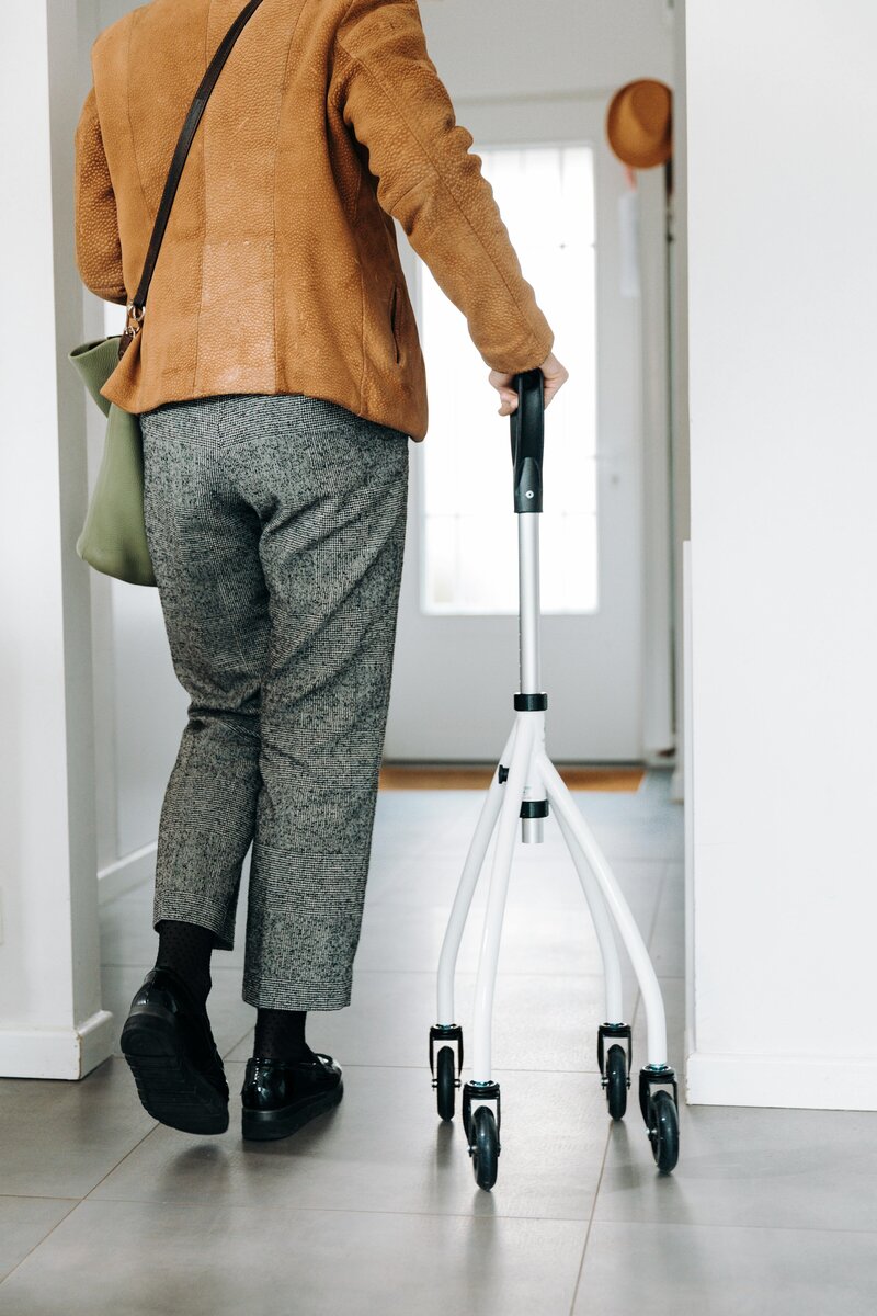 Individual using a cane walking out the door