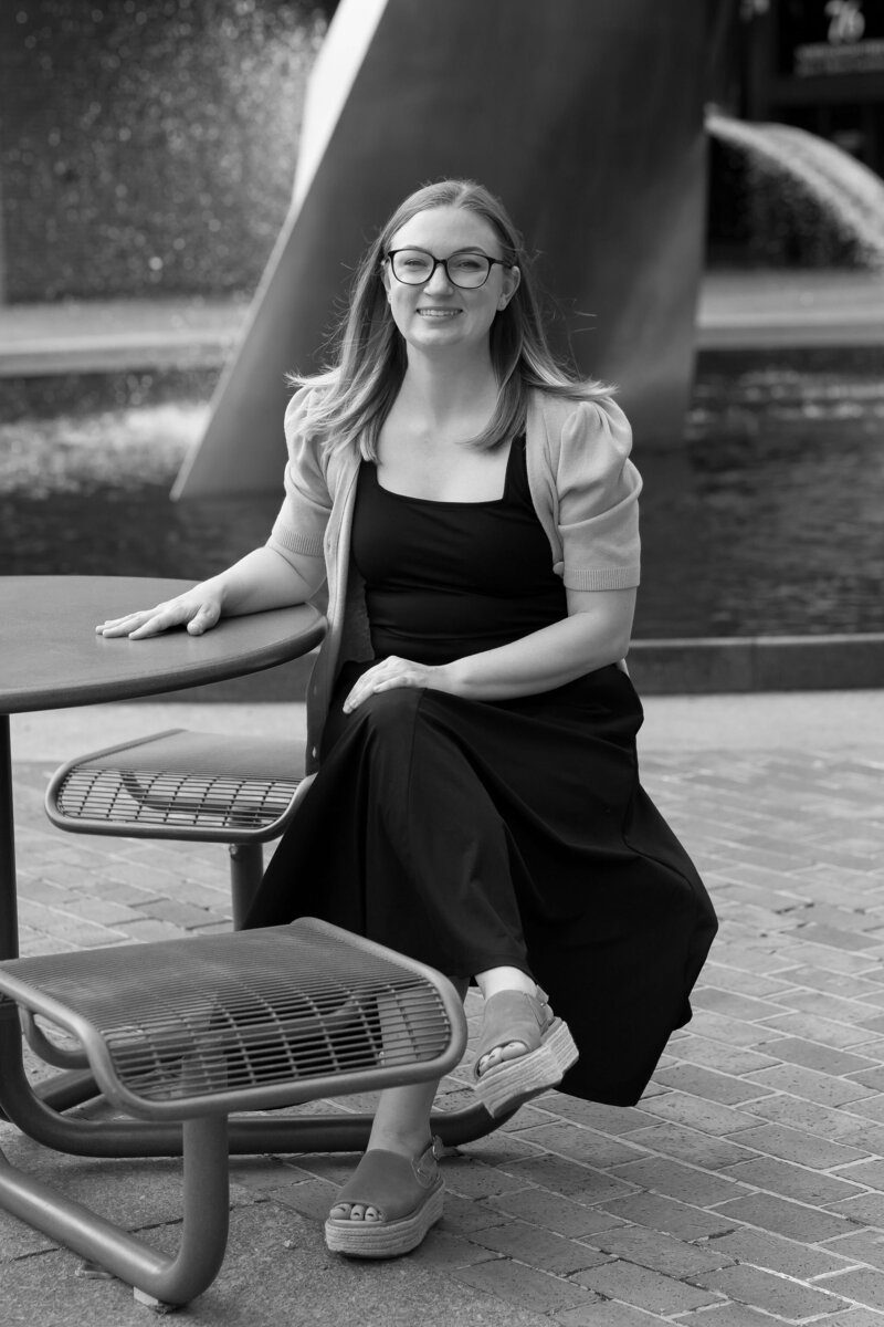 woman sitting at picnic table smiling in black and white