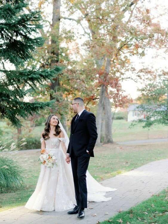 Bride and groom walk together at their fall wedding at Rust Manor