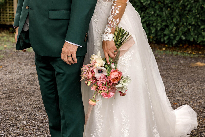 Close up of groom's green suit and bride's wedding bouquet