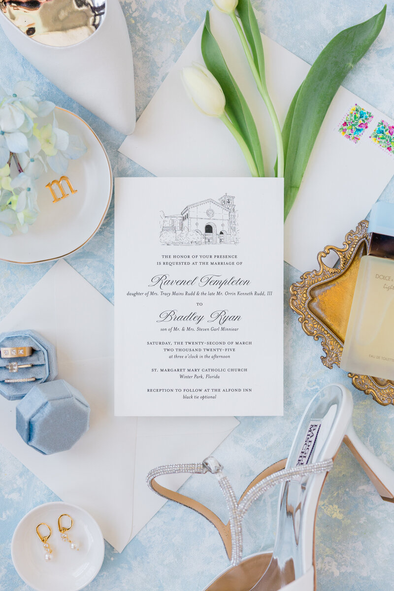 Photo of an invitation suite against a blue backdrop with all bridal details at the Alfond Inn, Winter Park. 