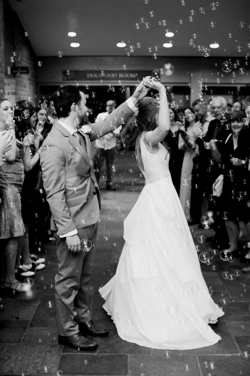 Bride and groom dancing during their grand bubble exit in Colonial Williamsburg, with guests blowing bubbles, coordinated by Sweet Caroline Events. Photo by Morgan Renee Photography.