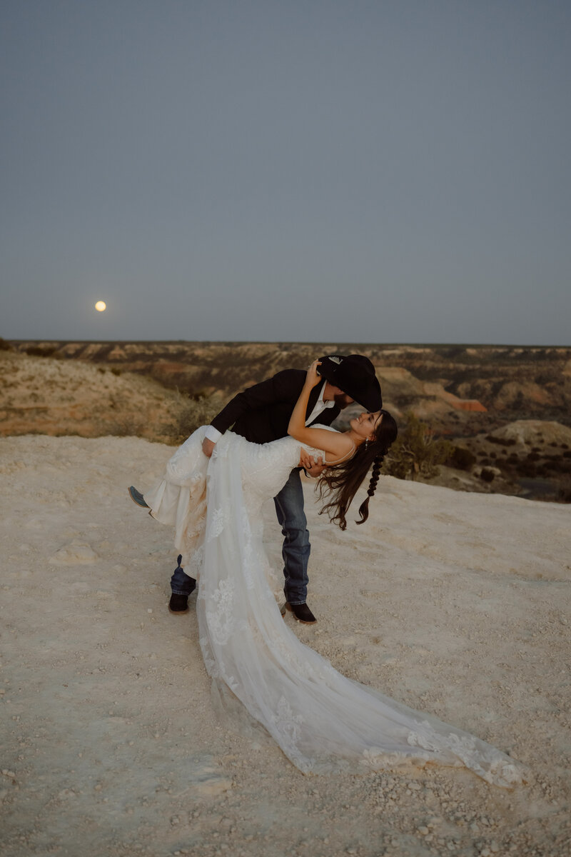 texas elopement couple dip kissing at dusk with a full moon behind them
